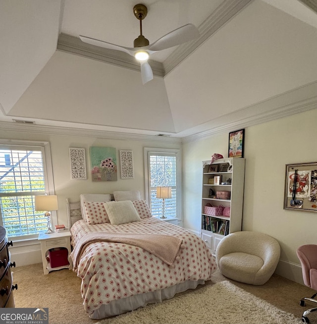 carpeted bedroom with a tray ceiling, a ceiling fan, and crown molding