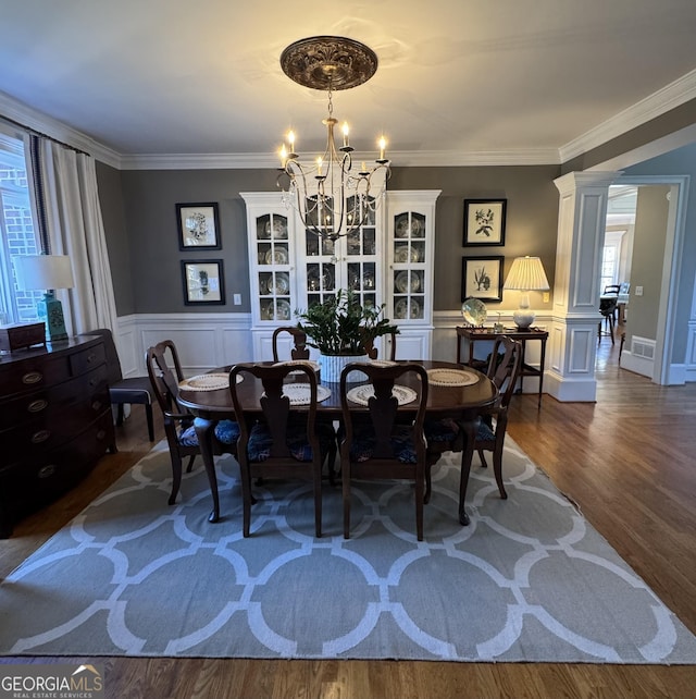 dining space featuring a healthy amount of sunlight, an inviting chandelier, dark wood finished floors, and ornate columns