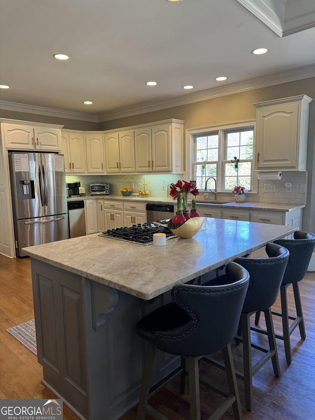 kitchen featuring stainless steel appliances, a kitchen island, a breakfast bar area, and wood finished floors