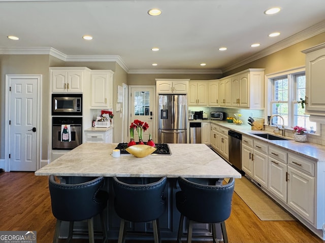 kitchen featuring a kitchen island, stainless steel appliances, a sink, and a kitchen breakfast bar