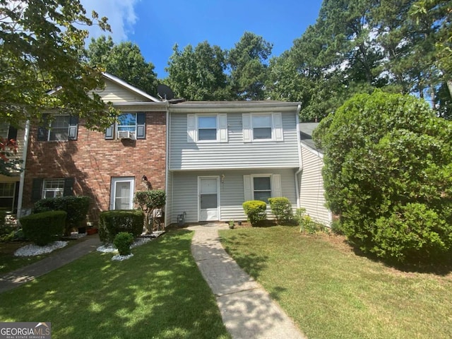 townhome / multi-family property with a front lawn and brick siding