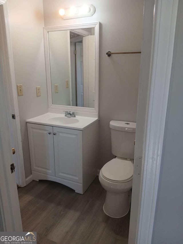 bathroom with toilet, wood finished floors, and vanity