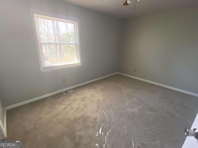 spare room with carpet floors, baseboards, visible vents, and ceiling fan