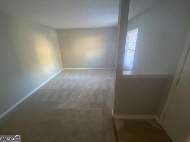 carpeted spare room featuring baseboards