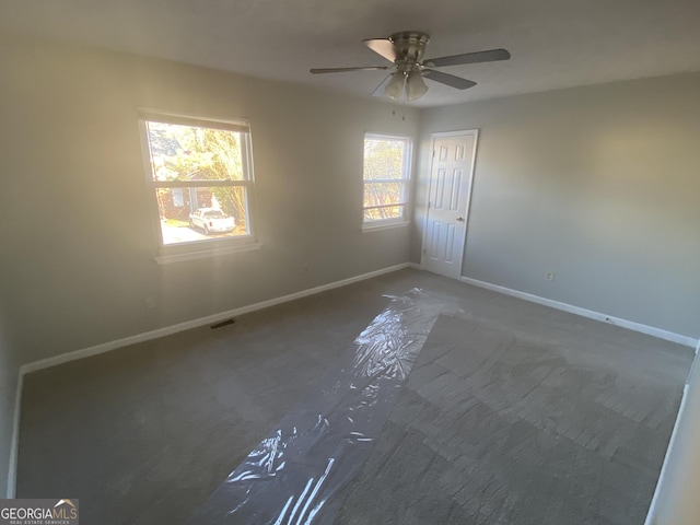 unfurnished room featuring a ceiling fan, visible vents, and baseboards