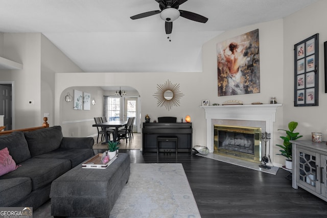 living room featuring ceiling fan, arched walkways, wood finished floors, vaulted ceiling, and a glass covered fireplace