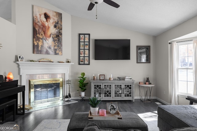 living room featuring lofted ceiling, baseboards, wood finished floors, and a glass covered fireplace