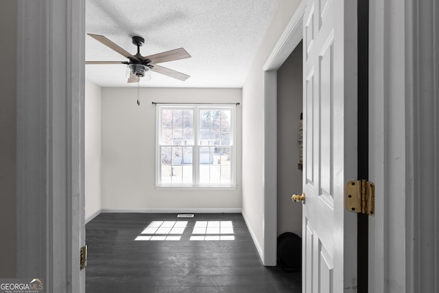 interior space with dark wood-style floors, ceiling fan, baseboards, and a textured ceiling