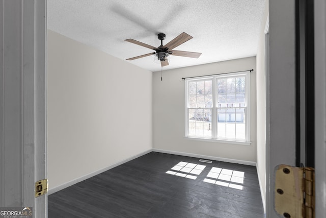 empty room with a textured ceiling, dark wood-style flooring, a ceiling fan, and baseboards