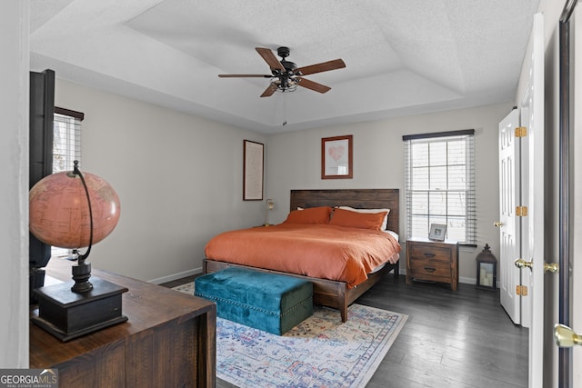 bedroom featuring hardwood / wood-style flooring, baseboards, a tray ceiling, and a textured ceiling