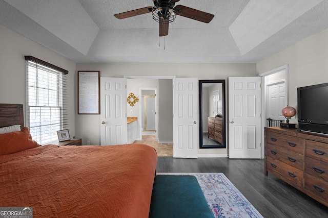 bedroom featuring a textured ceiling, dark wood finished floors, baseboards, a ceiling fan, and a raised ceiling