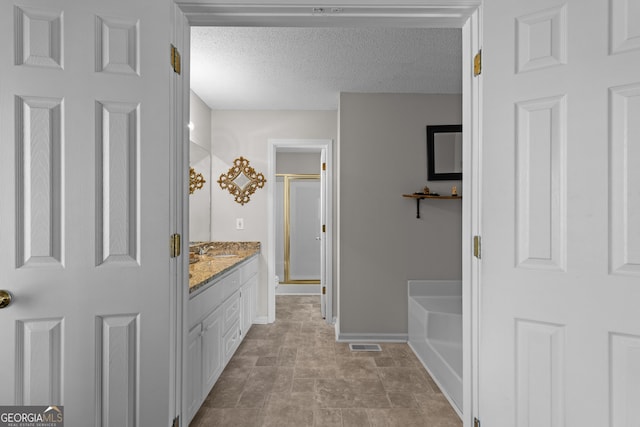 bathroom featuring a textured ceiling, a garden tub, vanity, visible vents, and a shower stall