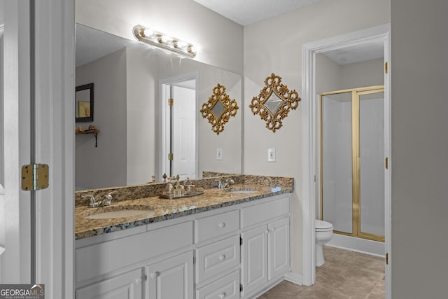 bathroom featuring a sink, a shower stall, toilet, and double vanity