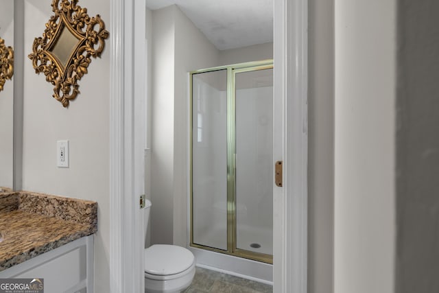 bathroom with toilet, a stall shower, and vanity