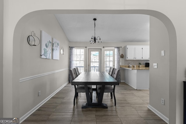 dining space with a notable chandelier, lofted ceiling, and baseboards