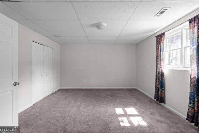 unfurnished bedroom with carpet, a paneled ceiling, a closet, visible vents, and baseboards