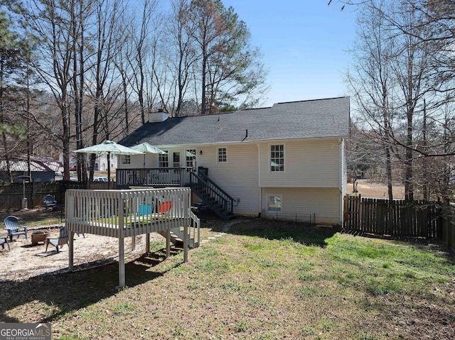 rear view of property featuring an outdoor fire pit, a fenced backyard, a wooden deck, and a lawn