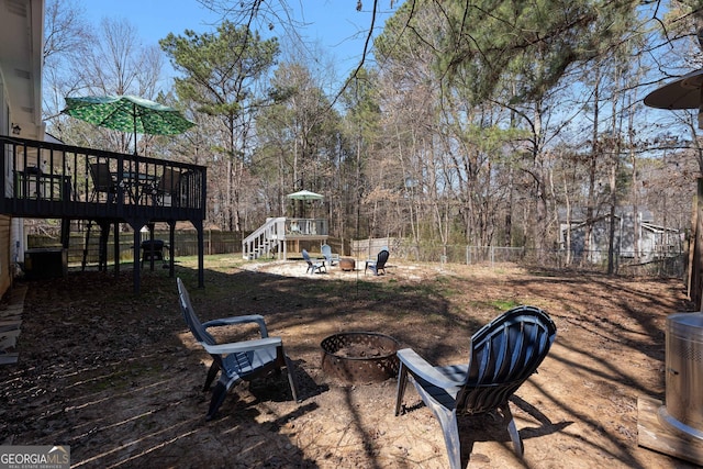 view of yard with stairs, a fire pit, fence, and a wooden deck