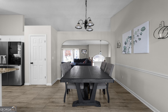 dining area featuring a chandelier, arched walkways, and baseboards