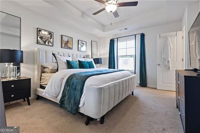 bedroom with a raised ceiling, visible vents, a ceiling fan, light carpet, and baseboards