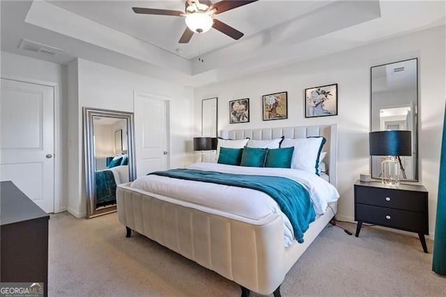 bedroom featuring ceiling fan, carpet flooring, visible vents, baseboards, and a raised ceiling