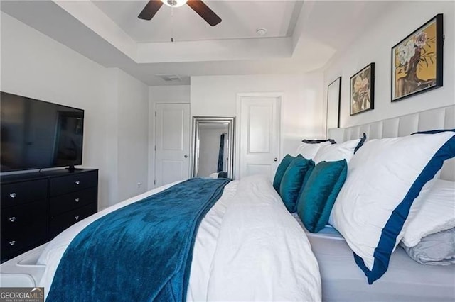 bedroom with a raised ceiling and ceiling fan