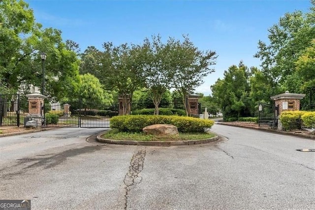 view of street with street lighting, a gate, curbs, and a gated entry