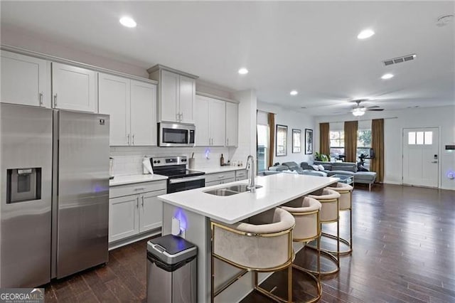 kitchen with dark wood finished floors, visible vents, decorative backsplash, appliances with stainless steel finishes, and a sink