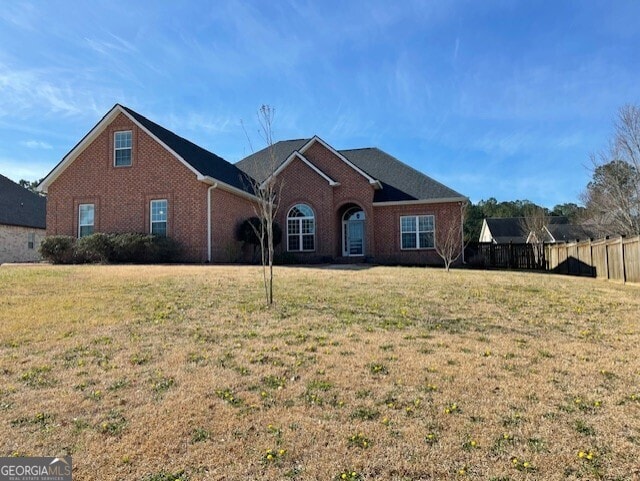 traditional-style home with a front lawn, fence, and brick siding