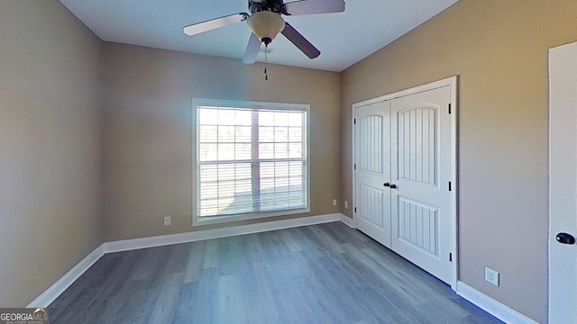 unfurnished bedroom featuring a closet, wood finished floors, a ceiling fan, and baseboards