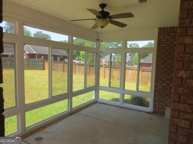 unfurnished sunroom featuring a ceiling fan and a residential view