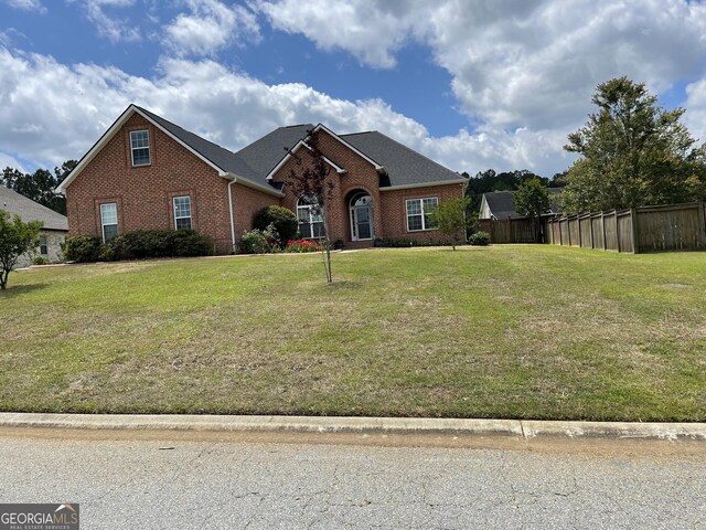 view of front facade featuring fence, a front yard, and brick siding