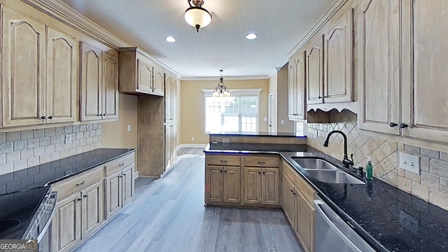 kitchen featuring appliances with stainless steel finishes, wood finished floors, decorative light fixtures, a peninsula, and a sink