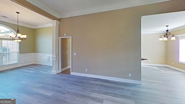 unfurnished room featuring ornamental molding, a notable chandelier, and decorative columns