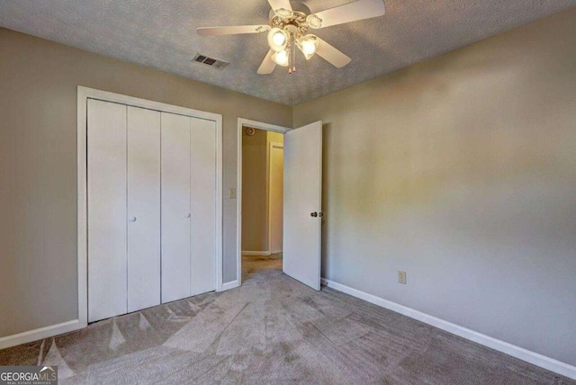 unfurnished bedroom with carpet, a closet, visible vents, a textured ceiling, and baseboards