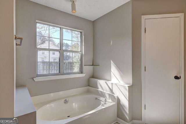 full bath featuring a textured ceiling and a bath