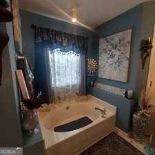 full bath featuring vaulted ceiling and a garden tub