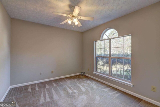 spare room featuring a textured ceiling, carpet, a ceiling fan, and baseboards