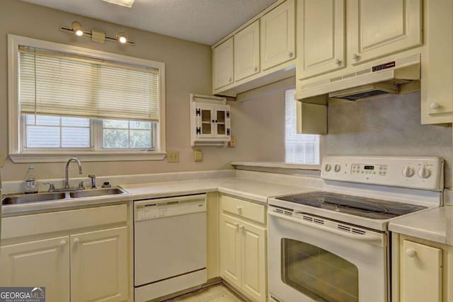 kitchen with light countertops, a sink, a textured ceiling, white appliances, and under cabinet range hood