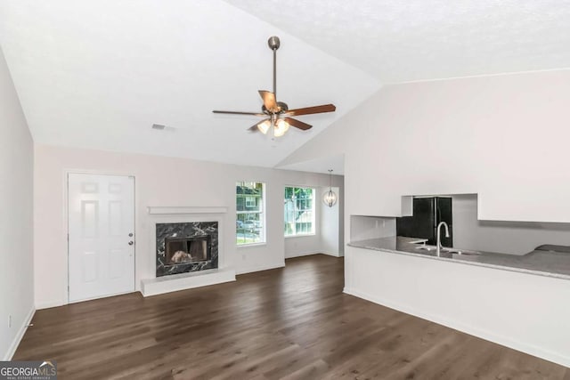 unfurnished living room with baseboards, a ceiling fan, a premium fireplace, dark wood-style flooring, and vaulted ceiling