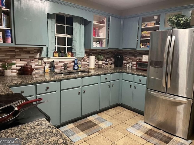 kitchen featuring light tile patterned floors, a sink, stainless steel fridge with ice dispenser, open shelves, and tasteful backsplash