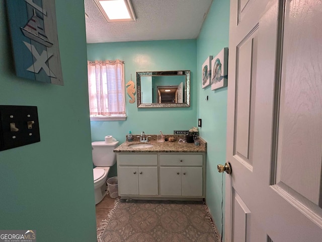 bathroom with toilet, a textured ceiling, and vanity