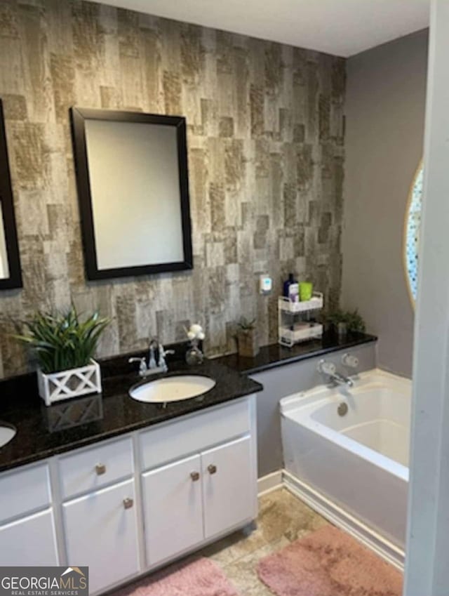 full bath featuring double vanity, a garden tub, and a sink