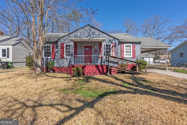 view of front facade featuring a front yard, concrete driveway, covered porch, and an attached carport