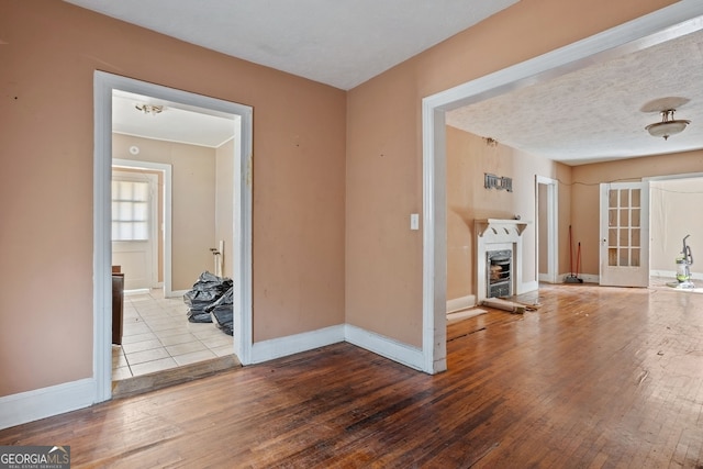 unfurnished living room featuring baseboards, a fireplace, a textured ceiling, and hardwood / wood-style floors