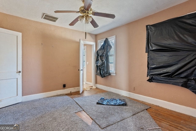 interior space with a ceiling fan, wood finished floors, visible vents, and baseboards