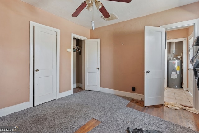 unfurnished bedroom featuring baseboards, visible vents, ceiling fan, electric water heater, and carpet flooring