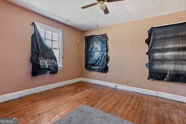 interior space with ceiling fan, wood-type flooring, and baseboards