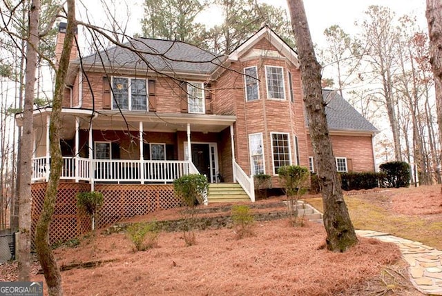 view of front of house with covered porch, a chimney, and roof with shingles