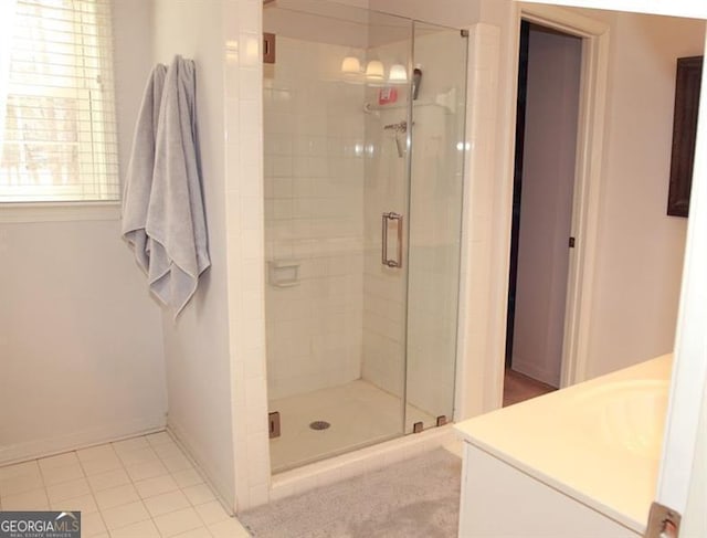 bathroom featuring tile patterned flooring, baseboards, a shower stall, and vanity